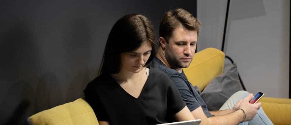 Couple on a couch using a tablet and a smartphone at home