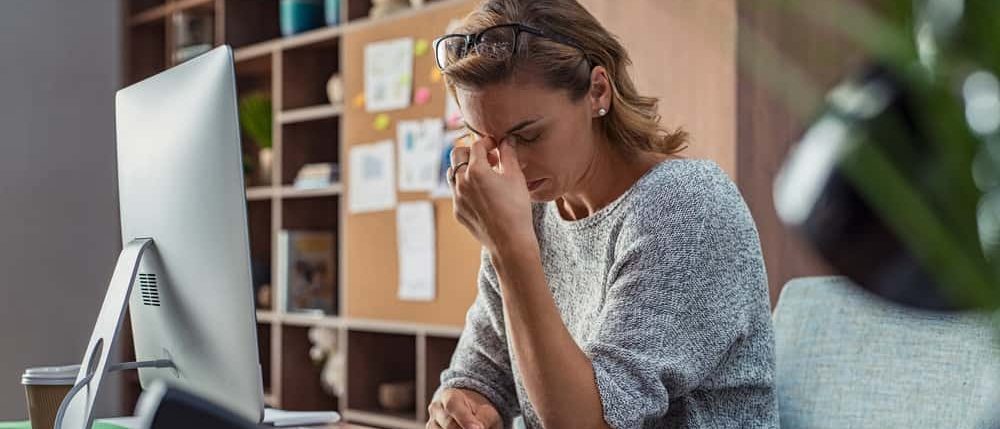 Frustrated woman holding her forehead while working at a desk